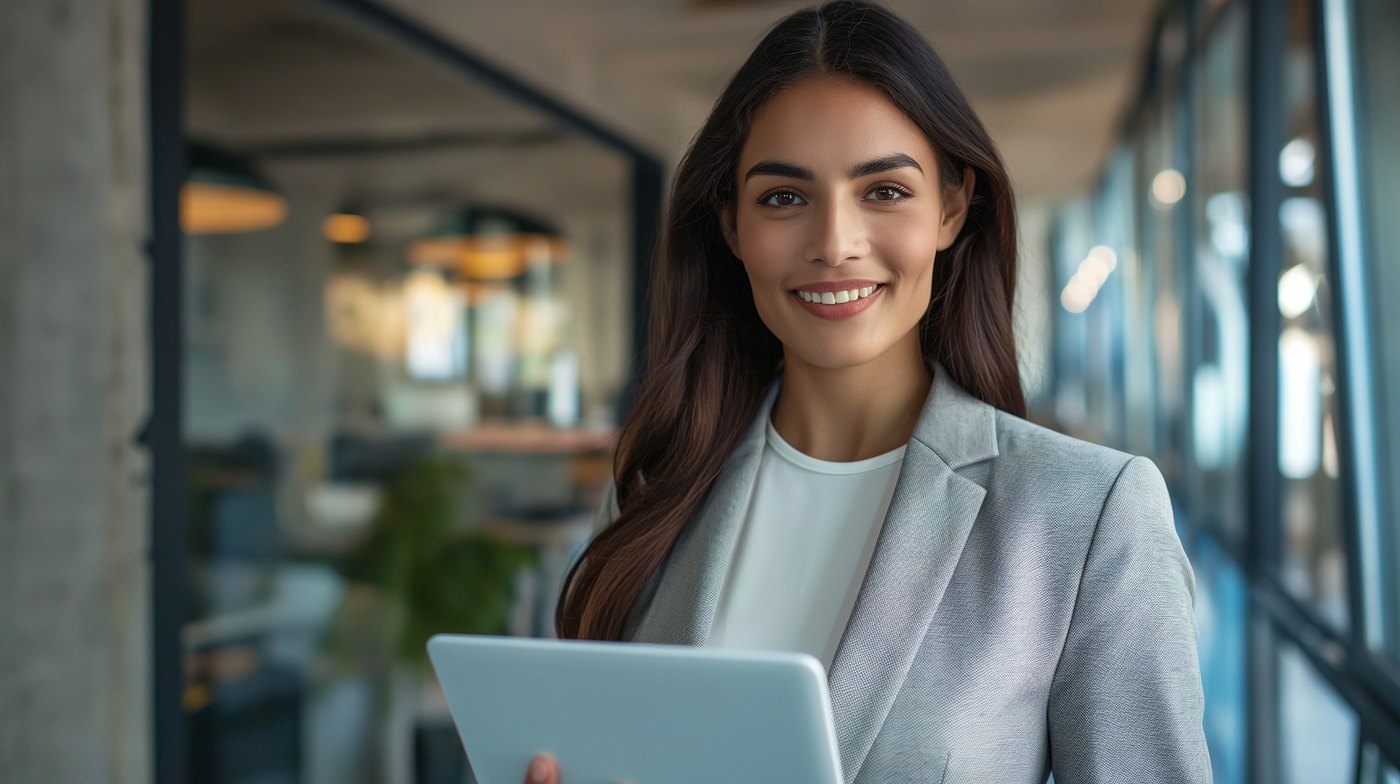 Professional woman holding a tablet in a bright modern office.